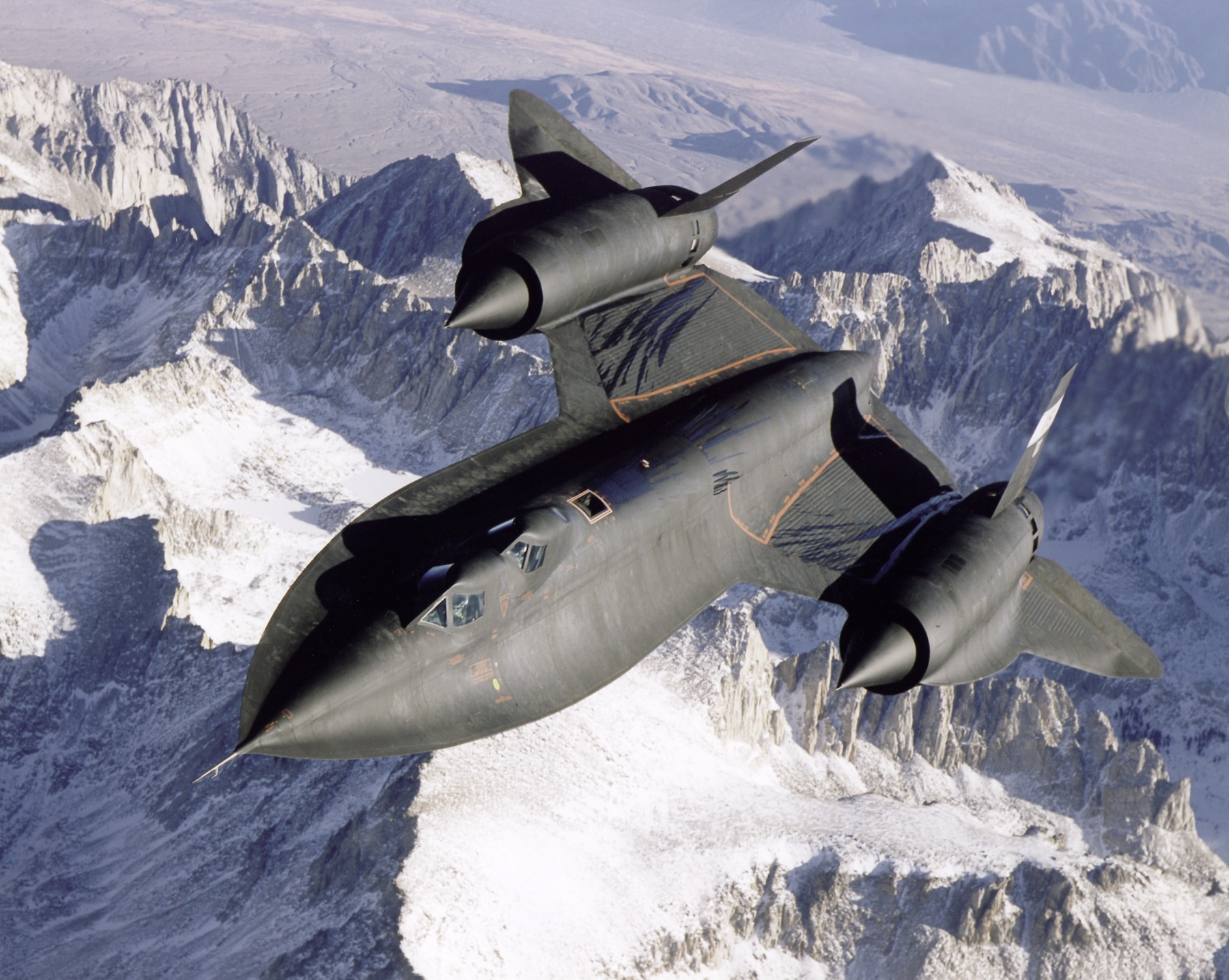 Lockheed SR-71 Blackbird over snow-capped mountains (NASA photo, 1995) — the Skunk Works' best-known Cold War product.