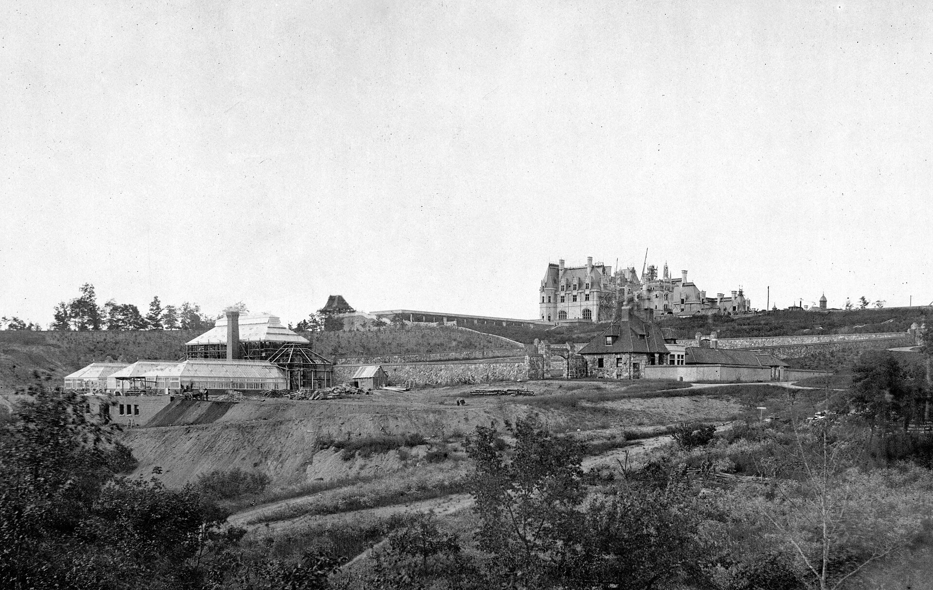 The Biltmore Estate under construction in the 1890s — the Vanderbilt house outside Asheville, still the largest privately-owned home in America. The Smokies' deep forests close behind Biltmore; this is the rim of the same Appalachian wilderness Eric Rudolph hid in for five years.