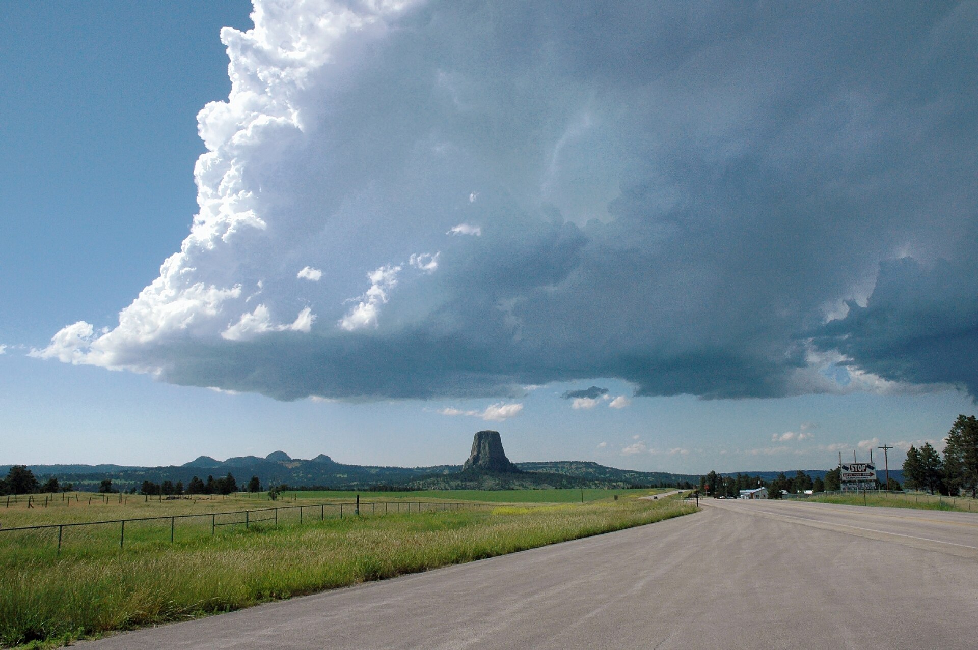Devils Tower beneath a cumulonimbus. Spielberg's 1977 Close Encounters of the Third Kind made it the cinematic stand-in for first contact; the visitor center reports a measurable bump in attendance every time the film airs.