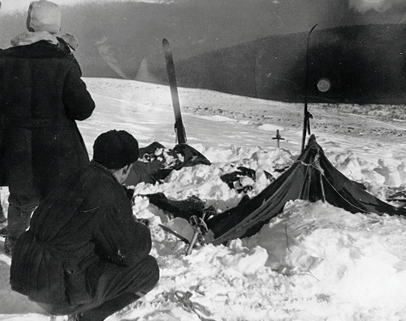 The Dyatlov tent as Soviet investigators found it, 26 February 1959 — collapsed, the side cut open from the inside, the skiers' equipment still in place. Igor Dyatlov's group of nine had abandoned shelter into −30°C wind and walked, mostly barefoot, into the dark.