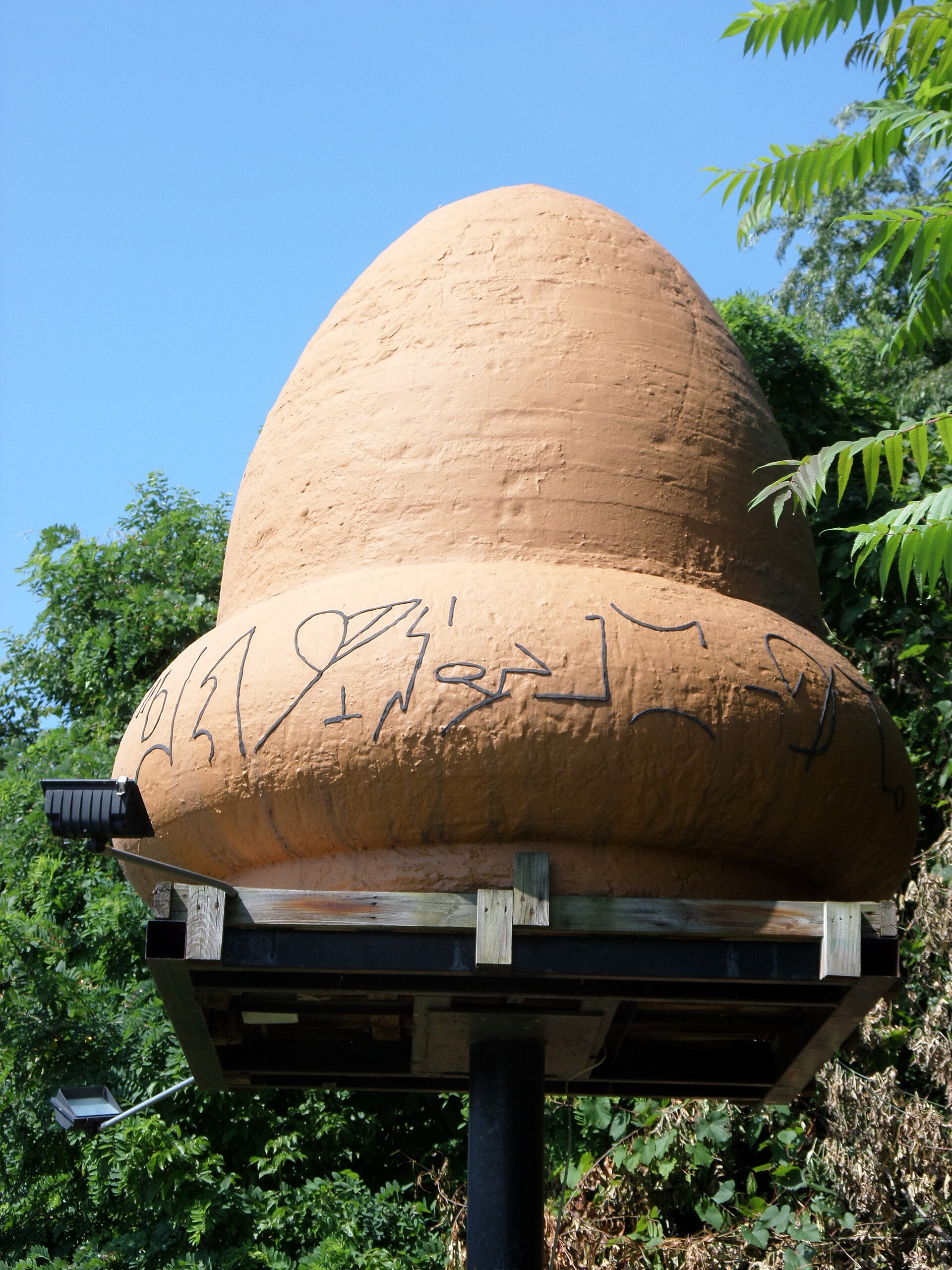 An angled view of the Kecksburg 'acorn' monument. The shape — roughly truncated bell with hieroglyph-like markings around the base — comes from the testimony of John Murphy, a WHJB radio reporter who reached the site before military personnel arrived.