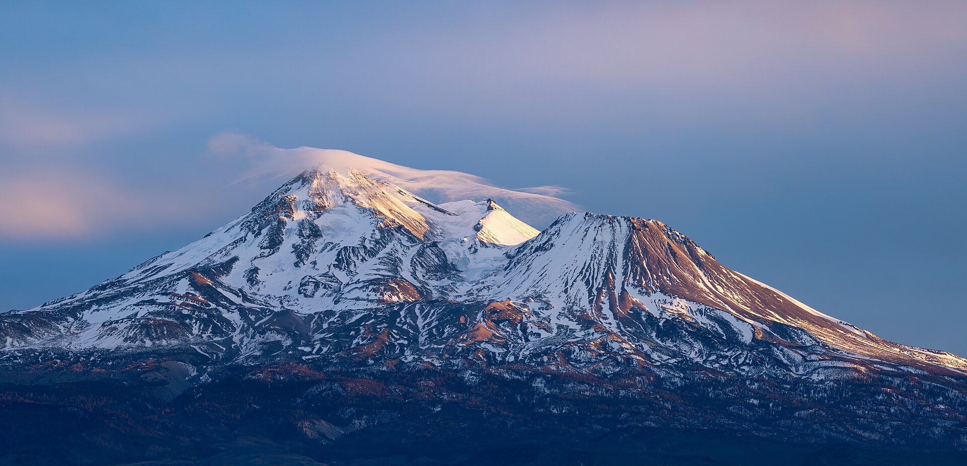 North face of Mount Shasta at sunset — a stratovolcano rising 14,179 feet, visible from 140 miles. Theosophist tradition places the Lemurian survivors inside its lava tubes.